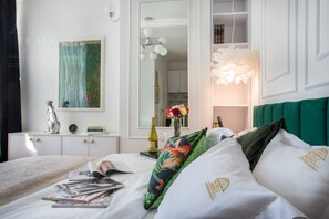 Ein ordentlich eingerichtetes Hotelzimmer mit einem Bett, einem Nachttisch mit Lampe, einem Spiegel und einem Bild an der Wand.