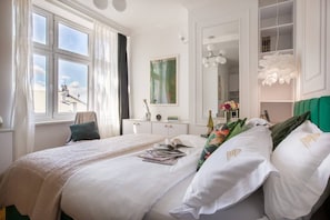 A hotel room with a large bed, a desk, a chair, a mirror, and a window with curtains. - Feniks Smaragd studio - no view (Kraków - Feniks)