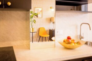 A modern kitchen with a sink, a bowl of fruit, a yellow chair, and a potted plant. - Feniks Sunblush studio with terrace (Kraków - Feniks)