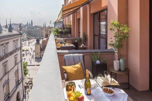 A balcony with a table set for a meal, a bottle of wine, and a view of the cityscape. - Feniks Sunblush studio with terrace (Kraków - Feniks)