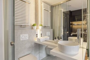 Ein modernes Badezimmer mit einem großen Spiegel, zwei Waschbecken, einer Toilette und einer Duschkabine.