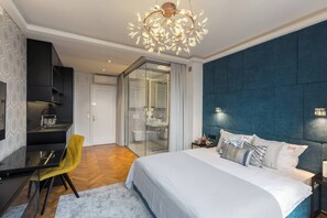 Une chambre d’hôtel moderne dotée d’un grand lit, d’un bureau, d’une chaise, d’une douche en verre et d’un luminaire au plafond au design original.