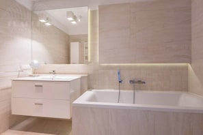 A modern bathroom with a white vanity, a large mirror, a bathtub, and a wall-mounted towel rack. - Apartment Serene 3-bed (Kraków – Old Town)