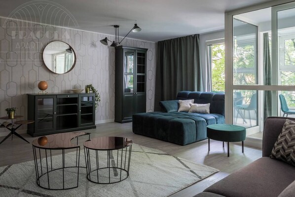 A modern living room with a sofa, a round mirror, a cabinet, and a dining table.