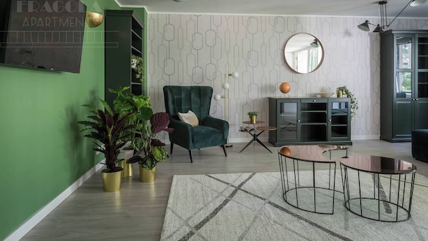 A living room with a green armchair, a round mirror, a globe on a cabinet, and a small table with a globe. - Apartment Serene 3-bed (Kraków – Old Town)