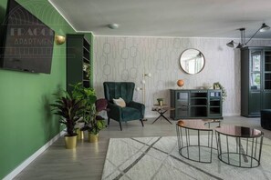 A living room with a green armchair, a round mirror, a globe on a cabinet, and a small table with a globe.