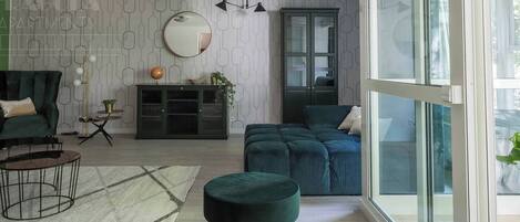Una sala de estar moderna con un sofá, un reposapiés y una vitrina de vidrio.