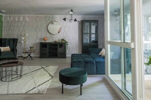 Een moderne woonkamer met een bank, een voetenbankje en een glazen kast.