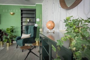 A green-themed living room with a teal armchair, a globe, and potted plants.