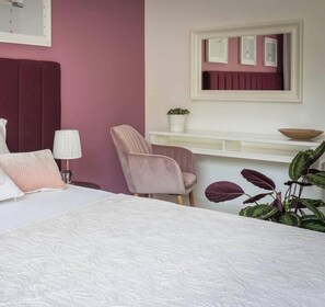 A bedroom with a bed, a chair, a bedside table with a lamp, a mirror, and a potted plant. - Apartment Serene 3-bed (Kraków – Old Town)