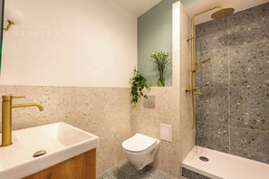 A bathroom with a freestanding bathtub, a toilet, and a sink with a gold faucet.