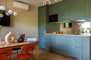 A modern kitchen with a microwave, stove, and sink. There is a dining table with chairs and a vase.