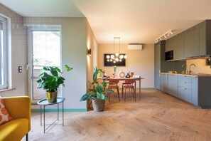 Een modern appartement met een eethoek, keuken en een gele fauteuil.