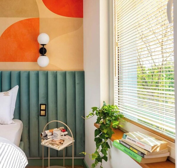 Un dormitorio con cama, mesita de noche y ventana con persianas.