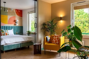 Un dormitorio con cama, mesita de noche, silla y ventanas amplias.