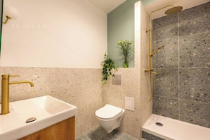 Un baño con una bañera independiente, un inodoro y un lavamanos con grifo dorado.