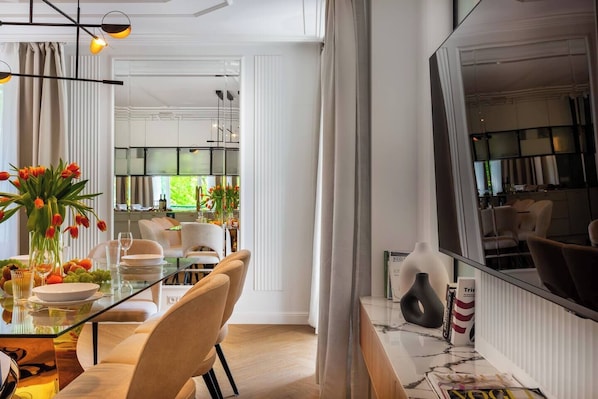 Uma zona de refeições moderna com uma mesa de vidro, cadeiras e um vaso de flores.