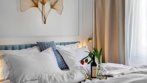 A neatly made bed with white and blue pillows, a decorative wall piece, and a bedside table with a bottle and glass.