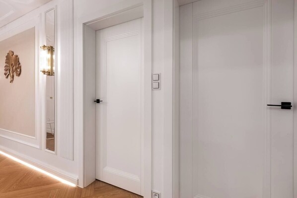 Un pasillo con puertas blancas, un accesorio de iluminación y un adorno en la pared.