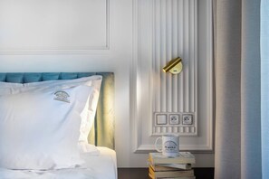 A neatly made bed with a pillow, a bedside table with a mug, and a wall-mounted light fixture.