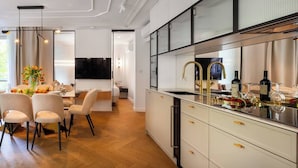 A modern kitchen with a built-in oven, a stainless steel sink, and a dining area with a table and chairs.