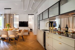A modern kitchen with a built-in oven, a stainless steel sink, and a dining area with a table and chairs.