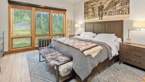 A bedroom with a large bed, wooden headboard, and a view of a forest through floor-to-ceiling windows. - Terraces A+ TRUE Ski-In Ski-Out 2 Bedroom, 2 Bathrooms - Sleeps 4 (Mountain Village)