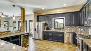 A modern kitchen with dark cabinetry, stainless steel appliances, and a wooden floor. - Hot Tub + Fire Pit: Possum Kingdom Lake Retreat! (Caddo)