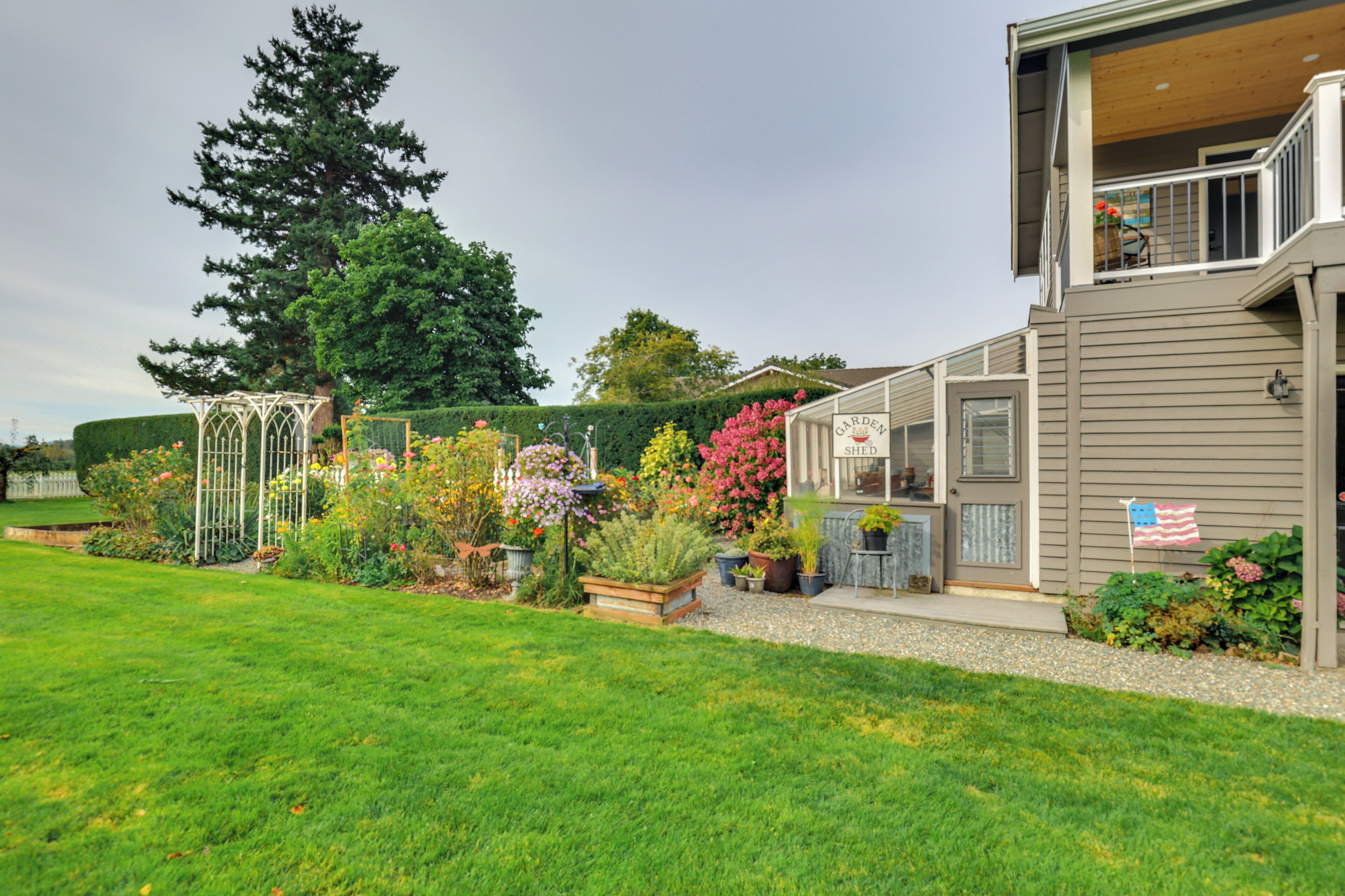 A residential property with a well-maintained garden, a pergola, and a two-story building with a visible deck.