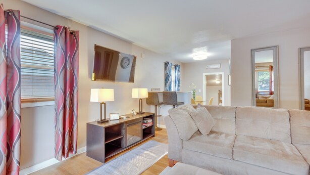 A living room with a beige sofa, two lamps, a TV, and a wooden cabinet. - 4 Mi to Dtwn: Home w/ Fenced Yard in Portsmouth! (Portsmouth)