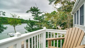 A wooden deck with a white railing overlooking a lake, surrounded by trees. - Swim & Fish On-site! Waterfront Cape Cod Cottage (Mashpee)