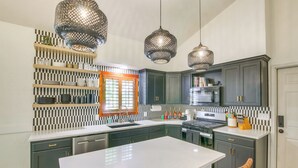 A modern kitchen with dark cabinets, a white countertop, and pendant lighting. - Smithfield Retreat: Ideal for Family Gatherings! (Smithfield)