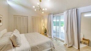 A bedroom with a bed, a ceiling light, a potted plant, and a view through a window. - Smithfield Retreat: Ideal for Family Gatherings! (Smithfield)