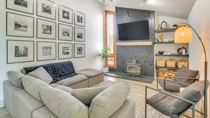 A modern living room with a fireplace, a sofa, a chair, and a wall decorated with framed pictures. - Smithfield Retreat: Ideal for Family Gatherings! (Smithfield)