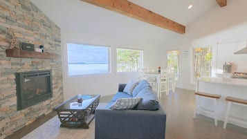 A spacious living area with a stone wall, a fireplace, a sofa, and a view of the sea.