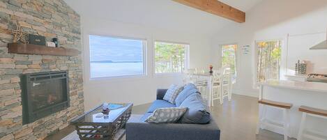 A spacious living area with a stone wall, a fireplace, a sofa, and a view of the sea.