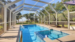 A covered swimming pool with a view of a park and a golf course in the background. - Waterfront Gulf Coast Home w/ Outdoor Oasis! (Gautier)