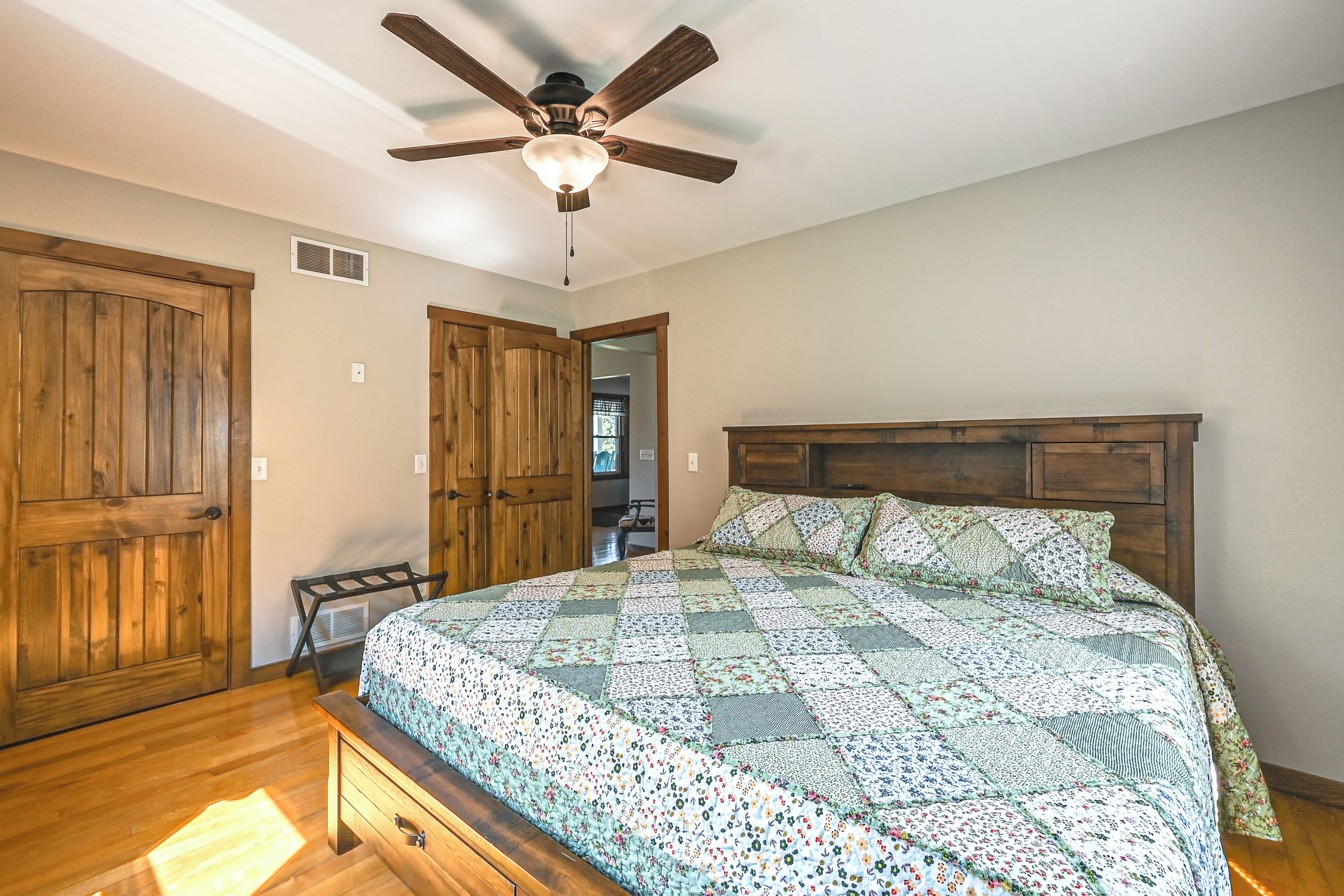 A bedroom with a wooden bed, a ceiling fan, and wooden doors.