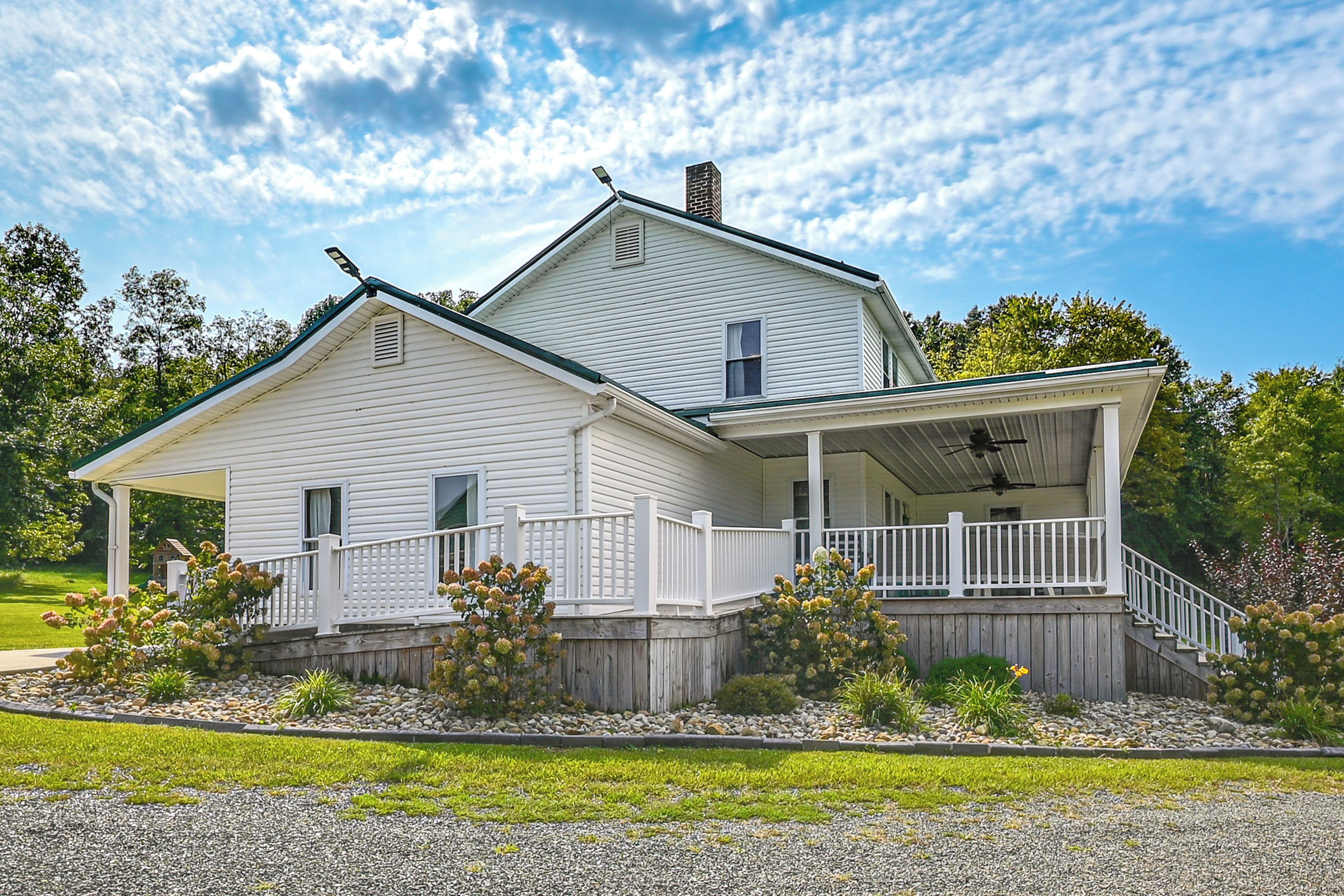 A two-story white house with a covered porch and a wooden fence.