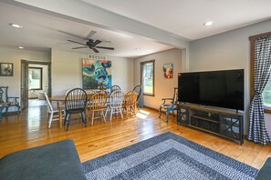 A spacious living room with a dining area, a ceiling fan, and a large flat-screen TV. - Wooded Escape w/ Pond & Grill in Pleasant City! (Pleasant City)