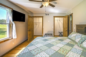 Quarto com cama grande, portas de madeira, ventilador de teto e vista para o exterior.