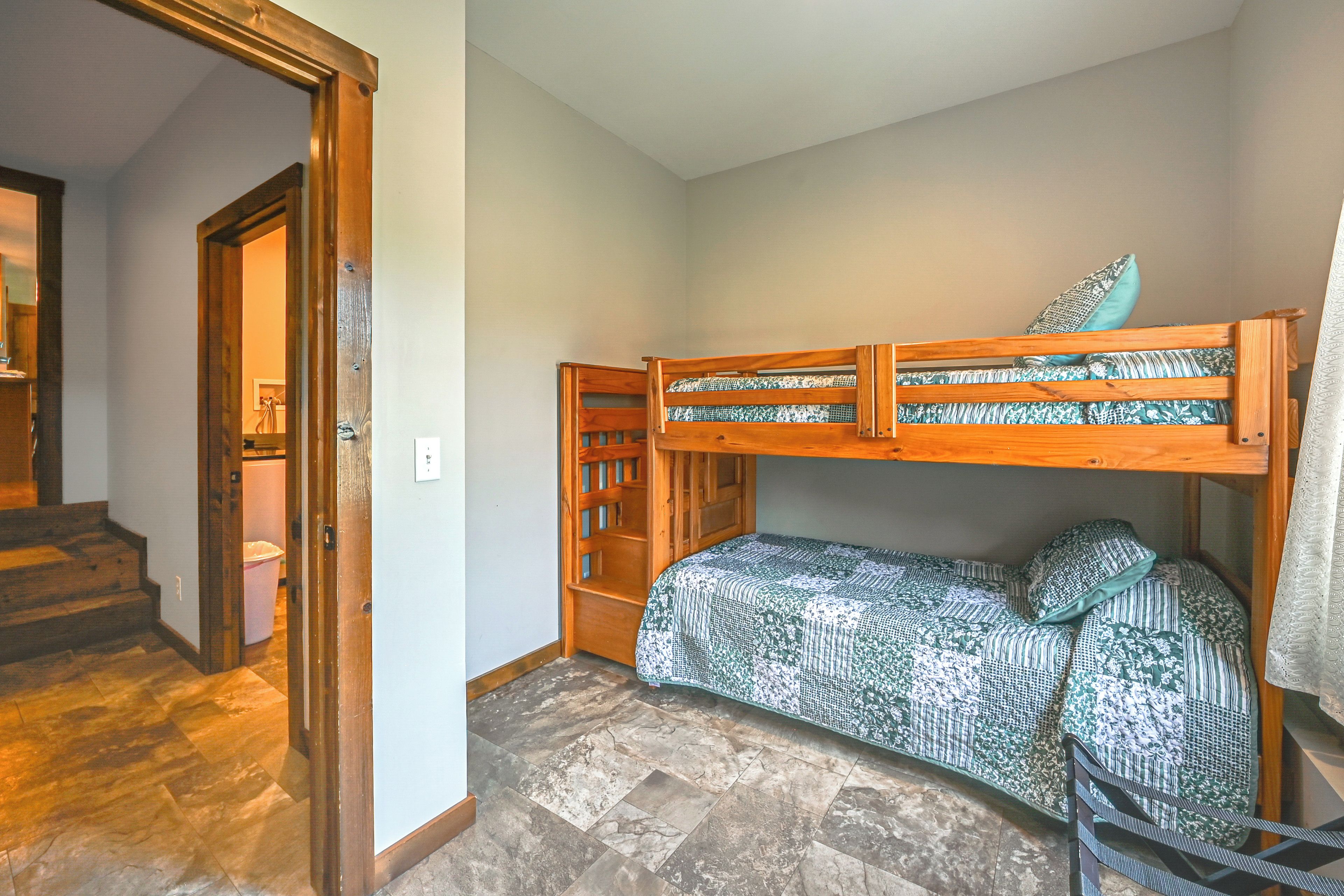 A room with a bunk bed, a wooden door, and a staircase leading to another area.