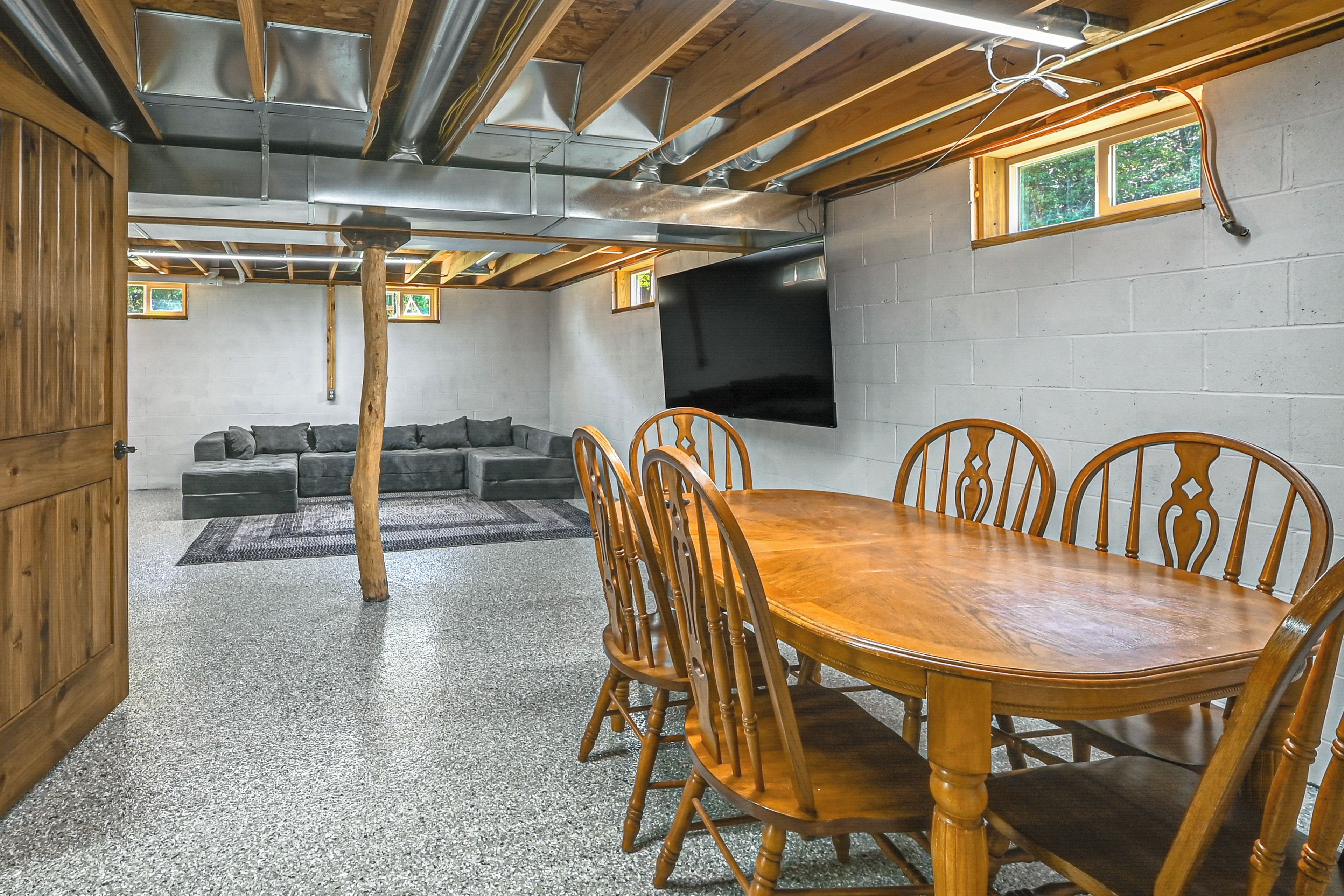 Una habitación con una mesa de comedor de madera, sillas, un sofá y un televisor de pantalla plana montado en la pared.