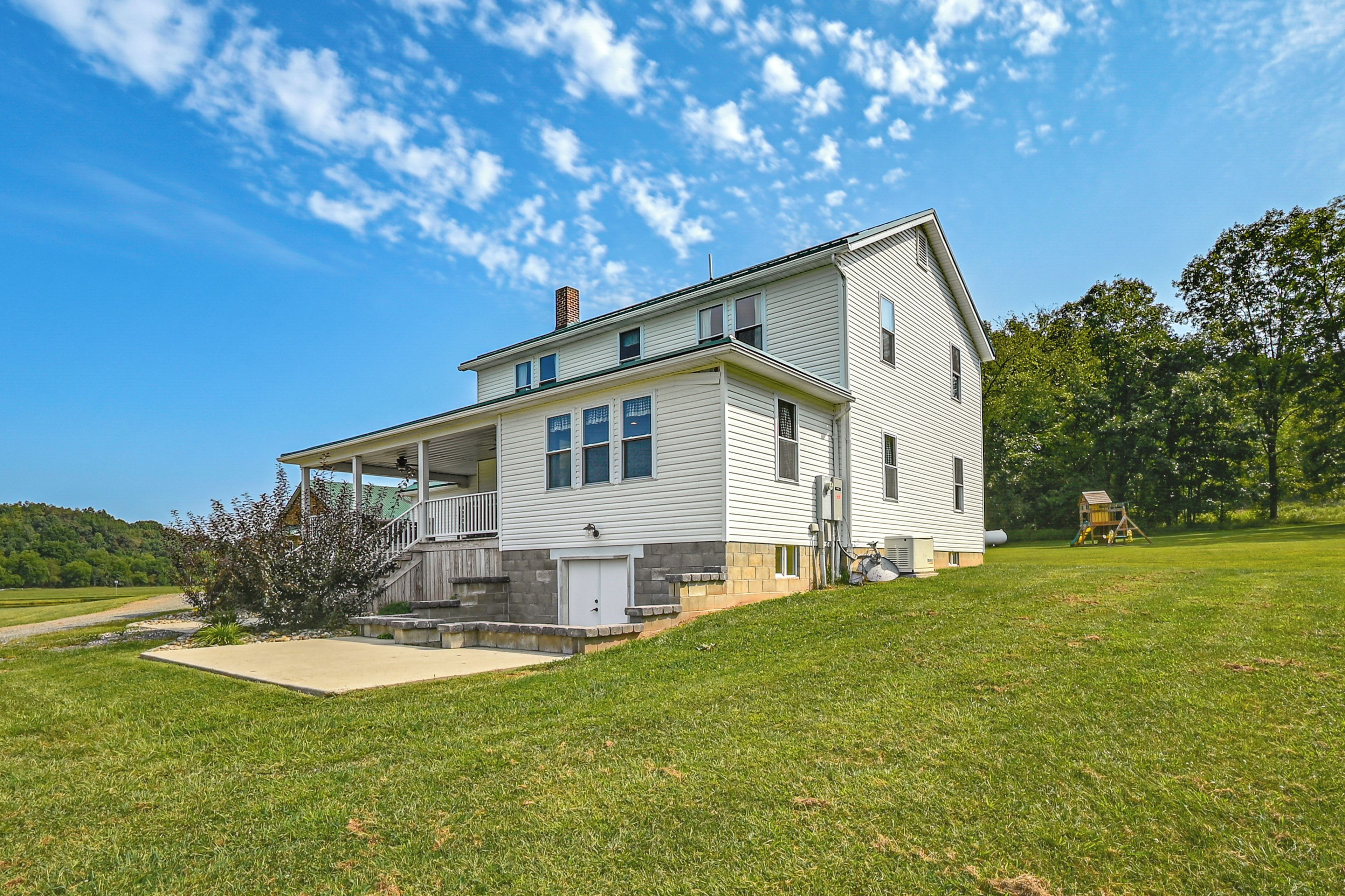 A two-story house with a covered porch, a front yard, and a small play area.