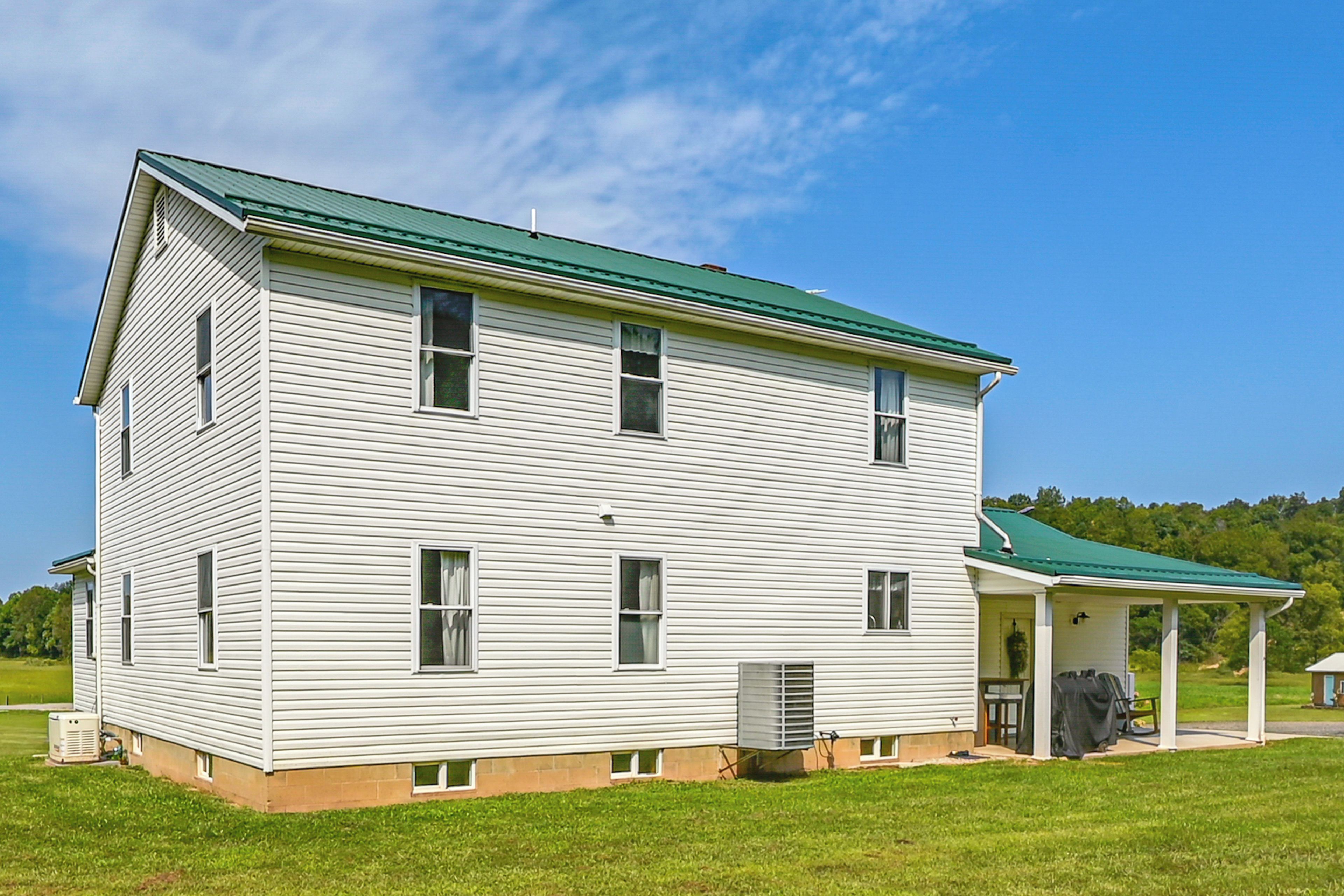 A two-story house with a green roof, a covered porch, and a small attached garage.