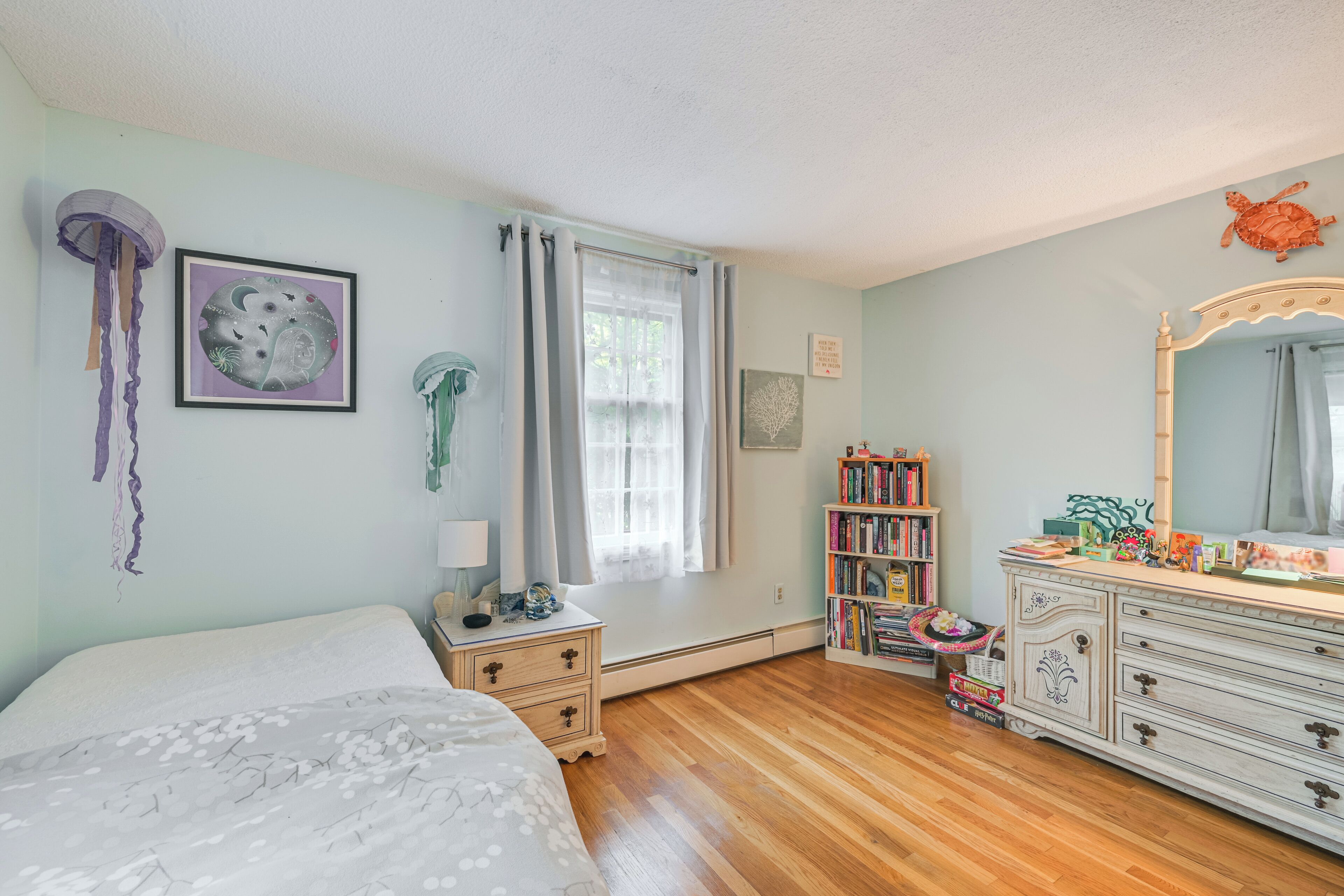 Ein Schlafzimmer mit Bett, Kommode und Bücherregal.
