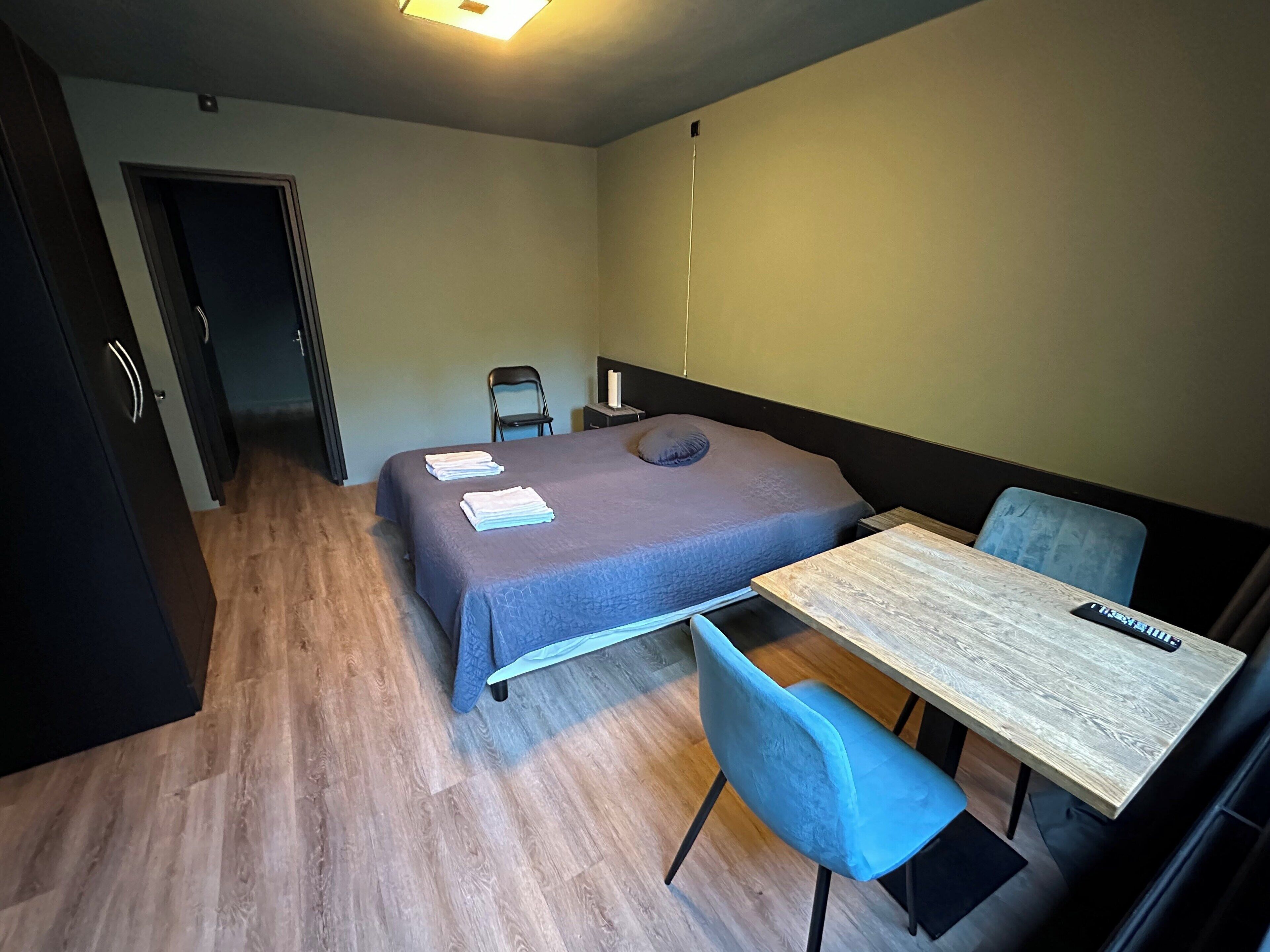 Ein kleines Zimmer mit einem Bett, einem Tisch, einem Stuhl und einem Schreibtisch.