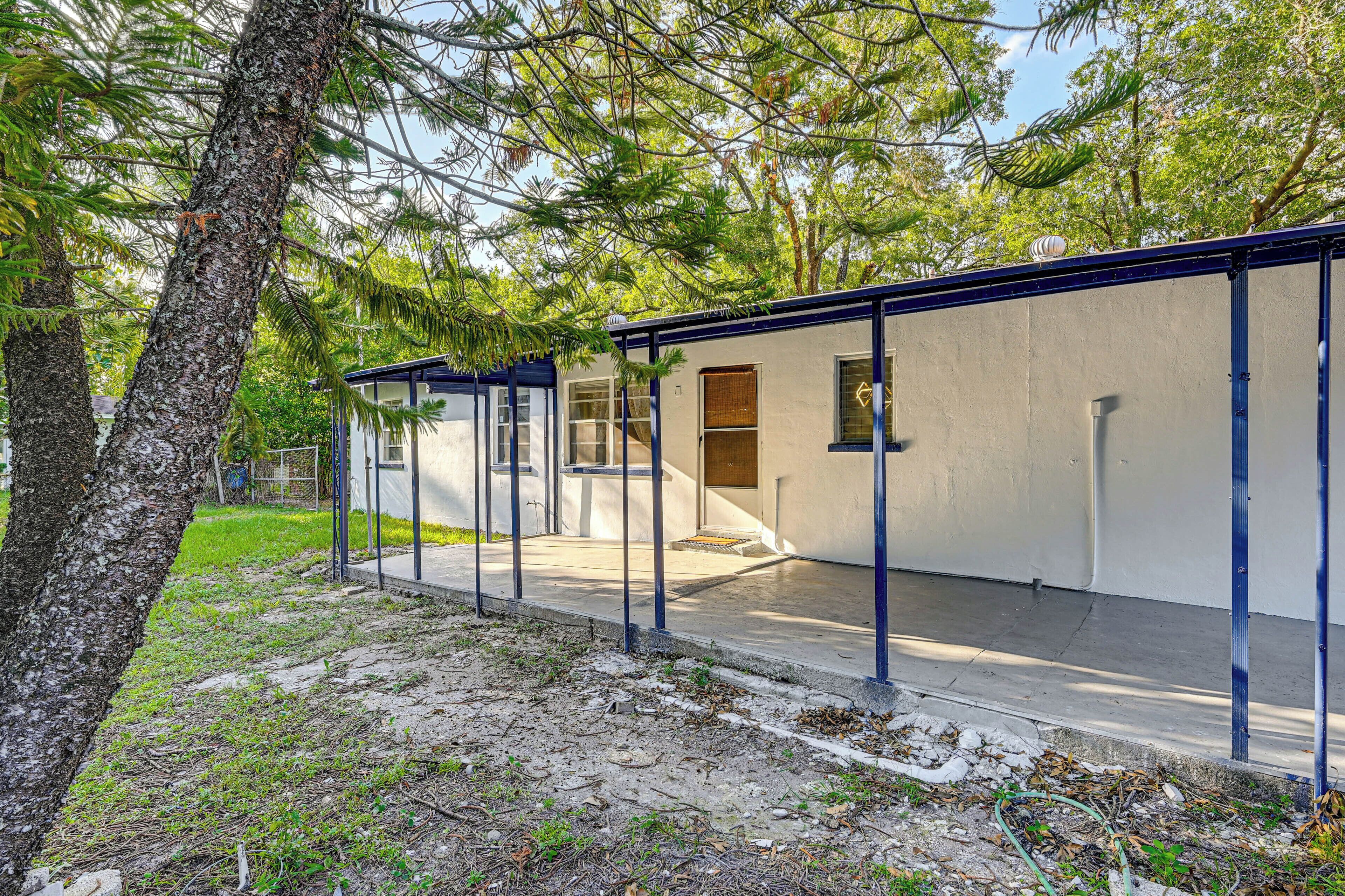 A row of single-story cabins with a covered patio area, surrounded by trees.