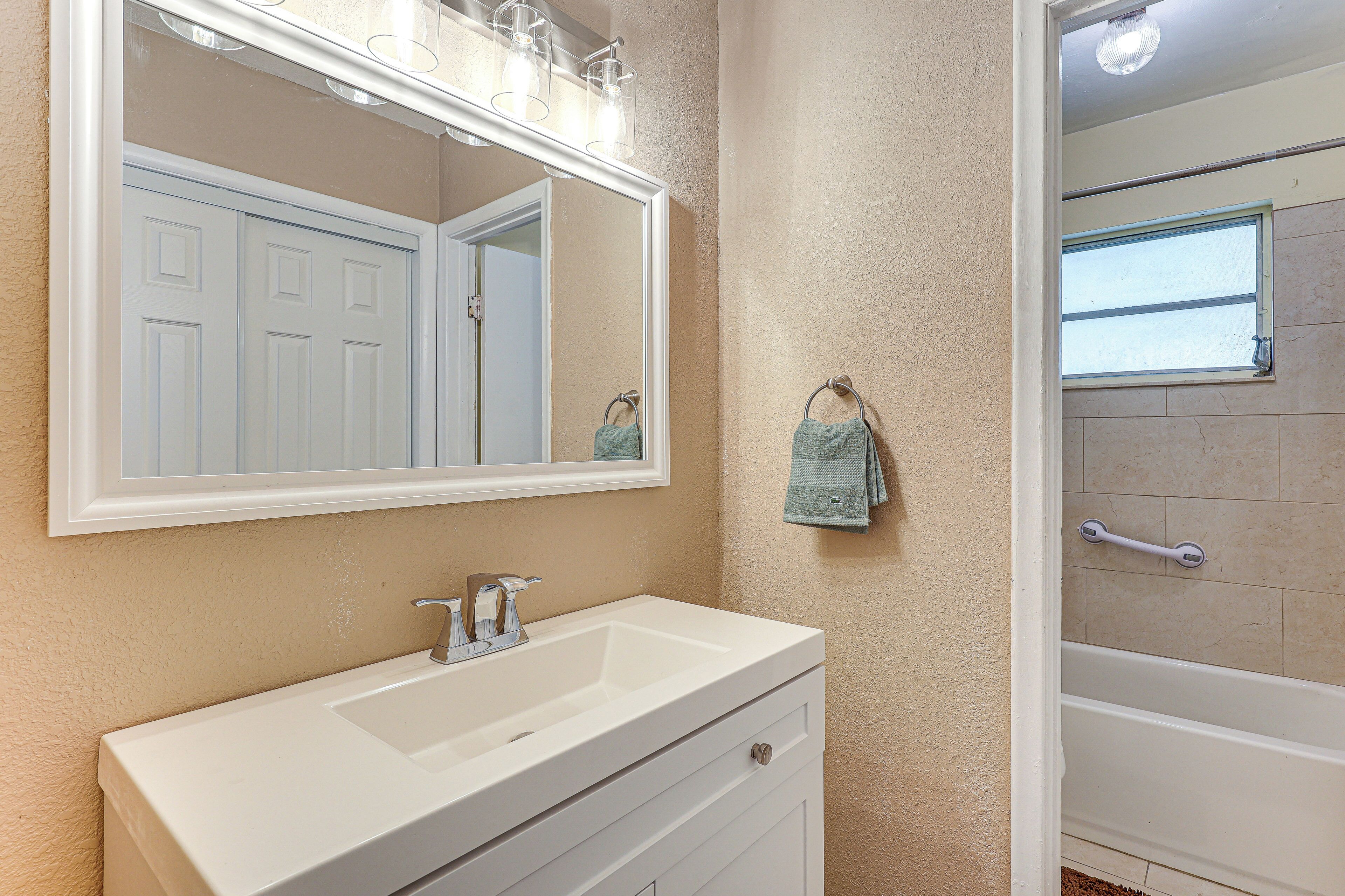 Une salle de bain avec un lavabo blanc, un grand miroir et un espace douche.