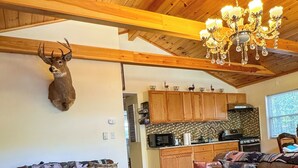Una sala de estar acogedora con techo de madera, cabeza de venado montada y una araña.